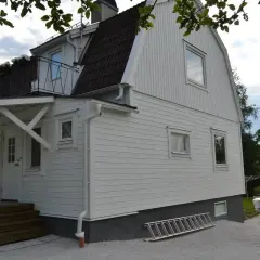 Vitt hus med ny fasad, trappa och en stege redo för arbete.