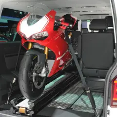 Una moto deportiva roja lista para transportar en furgoneta, asegurada con correas sobre un riel.