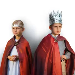 Dwóch chłopców w strojach hiszpańskich królów, z błyszczącymi koronami i czerwonymi pelerynami.