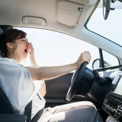 Mujer bostezando al conducir mucho tiempo sin descansar. El cansancio al volante es peligroso.