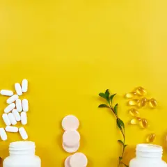 Weiße Pillen, Kapseln und Brausetabletten auf gelbem Grund. Informationen zu Chondroitin Nebenwirkungen sind wichtig, bevor man solche Präparate einnimmt.