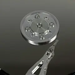 Wnętrze dysku twardego. Widoczny talerz magnetyczny i głowica. Dowiedz się, jak dodać dysk do komputera.
