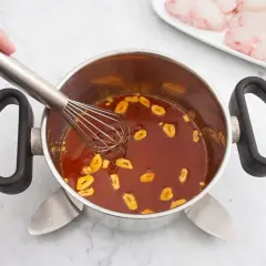 Batir salsa con ajo en una olla. En un plato, trozos de rape fisch listos para cocinar.