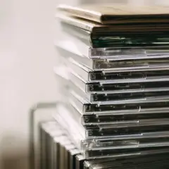 Stos przezroczystych pudełek z płytami CD, idealny do przechowywania nowości płytowych.
