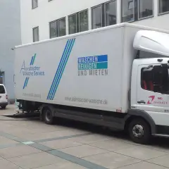 Ein LKW von Alpirsbacher Wäsche Service, der für Werkverkehr genutzt wird, steht vor einem Gebäude. Er transportiert Wäsche.
