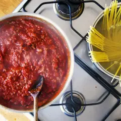 Gotowy do podania, aromatyczny sos do spaghetti gotuje się obok makaronu w garnku.