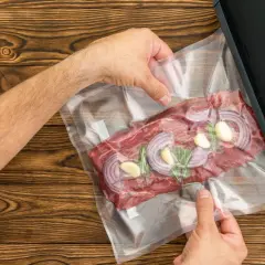 Mięso z cebulą i czosnkiem w woreczku do pakowania próżniowego. Czy można mrozić produkty pakowane próżniowo? Tak, to świetny sposób na zachowanie świeżości.