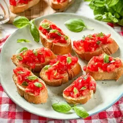 Frische italienische Crostini mit Tomaten und Basilikum auf einem Teller, garniert mit frischen Basilikumblättern.