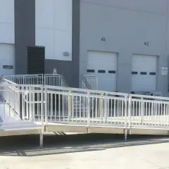 A modular wheelchair ramp system is installed outside a warehouse, providing accessibility to loading docks. This shows how to build a wheelchair ramp for easy access.
