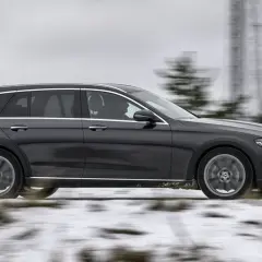 Mörkgrå Mercedes All-Terrain wagon kör på en snöig väg, redo för alla utmaningar.