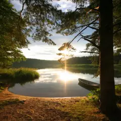 Zachód słońca nad jeziorem, łódka przy brzegu, idealne plaże na Mazurach.