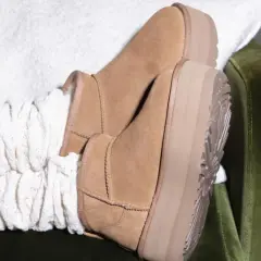 Pieds chaussés de bottes en daim UGG, avec des chaussettes blanches torsadées. Un aperçu de l'entretien chaussure daim.