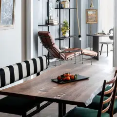 A large, live-edge wooden table with inlaid details, showcasing its impressive table dimension, is set with a tray of tangerines.