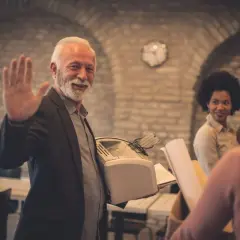 Un homme agite la main, tenant une imprimante. Il pourrait chercher un modèle de lettre de démission aide à domicile.
