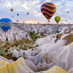 Balony unoszą się nad Kapadocją, tworząc malowniczy widok. To idealne miejsce na wakacje, gdzie można podziwiać piękno natury i poczuć się jak po szczepieniach na nudę w Turcji.