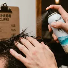 Un hombre aplica spray sal marina pelo para un look playero.