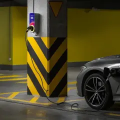 Szary samochód elektryczny ładuje się przy wallboxie. Ranking firm montujących ładowarki do samochodów elektrycznych.