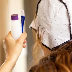 Persona se prepara para hacerse mechas en casa. Sostiene un kit para teñir el cabello y lleva un gorro especial.
