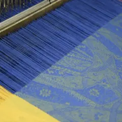 Le métier à tisser jacquard crée un motif complexe sur un tissu bleu et jaune.
