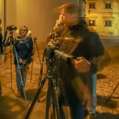 Uczestnicy kursu fotografii dla początkujących ćwiczą nocne zdjęcia na brukowanej uliczce.