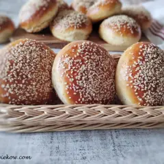 Świeżo upieczone bułki do burgerów, posypane sezamem, w wiklinowym koszyku. Idealne na domowe burgery.