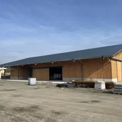 Nouveau bâtiment en bois, prêt à accueillir un atelier de menuiserie bois. Une tour de dépoussiérage est installée à côté.