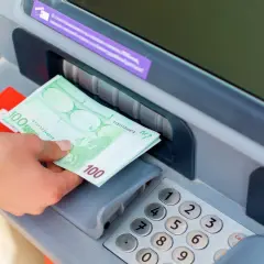 Ręka wyjmuje banknoty 100 euro z bankomatu. To pokazuje, gdzie można wypłacić euro z bankomatu.