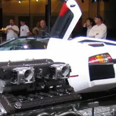 Biały Lamborghini Murcielago z otwartymi drzwiami i wyeksponowanym potężnym silnikiem V12.