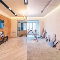 Remont starego domu wnętrze: z jednej strony gotowy salon z TV i kuchnią, z drugiej stan surowy z materiałami budowlanymi.