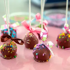 Chokladöverdragna cake pops med färgglada strössel och fina band. Perfekta för ett kalas!