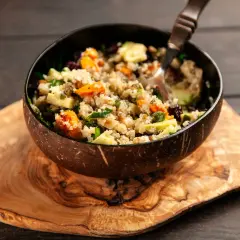 Kolorowa sałatka z komosy ryżowej z warzywami i suszoną żurawiną w misce z łupiny kokosa. Inspiracja na zdrowe quinoa przepisy.