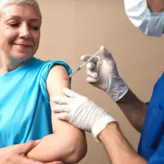 Uśmiechnięta kobieta otrzymuje szczepienie. Zastanawiasz się, ile kosztuje szczepionka na krztusiec? Zapytaj lekarza.
