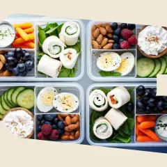 Vorbereitete Lunchboxen mit Wraps, Eiern, Beeren, Nüssen, Karotten und Gurken – perfekt für gesunde Snacks zum Mitnehmen.