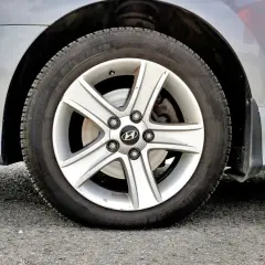 Koło samochodu z widocznym niskim ciśnieniem w oponach. Felga aluminiowa z logo Hyundai.