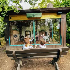 Dzieci oglądają bajkową scenkę w domku. To świetne atrakcje Kaszub dla dzieci, które przenoszą w świat fantazji.