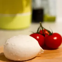 Frische Mozzarella und Kirschtomaten auf einem Holzbrett. Perfekt für eine leichte Mahlzeit während der Schwangerschaft.