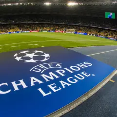 Logo Ligi Mistrzów UEFA na tle stadionu piłkarskiego.