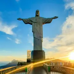 Christusstatue in Brasilien mit weit ausgebreiteten Armen, die den Sonnenuntergang über Rio de Janeiro überblickt.