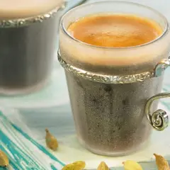 Dwie filiżanki kawy z pianką, obok strączki kardamonu. Zastanawiasz się, ile kardamonu do kawy dodać, by uzyskać ten aromat?