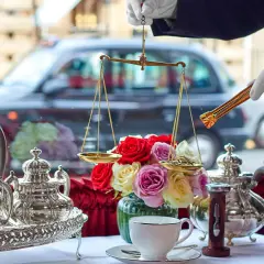 En elegant uppsättning för klassisk afternoon tea med silverkannor, en blomsterbukett och en våg för att mäta teblad.