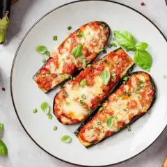 Berenjenas asadas con tomate y queso, un plato delicioso de recetas con berenjenas. Decoradas con albahaca fresca.