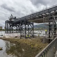 Obras en el puente de Santander, con andamios y trabajadores junto a la ría. Yates amarrados al fondo.