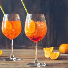 Dwa orzeźwiające Aperol Spritze z plastrem pomarańczy i słomkami. Aperol ma 11% alkoholu, idealny na letnie popołudnie.