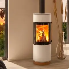 Gemütliches Wohnzimmer mit brennendem Kamin, der die Frage aufwirft: darf man im Sommer den Kamin anmachen? Sonnenuntergang draußen.