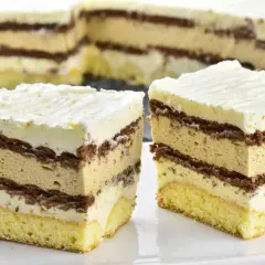 Pyszne ciasto caffe latte z warstwami biszkoptu, kremu kawowego i czekolady, zwieńczone bitą śmietaną.