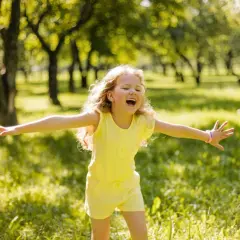 Niña feliz en un parque, disfrutando del sol. Su alegría refleja la autoestima en niños de 9 a 12 años.