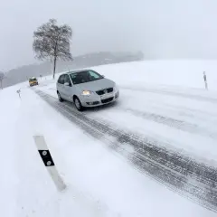 Coches circulando por carreteras con nieve en un día de invierno con poca visibilidad.