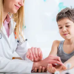Lekarka bada puls u dziecka, delikatnie dotykając jego nadgarstka.