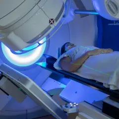 Frau liegt auf einem Tisch, während grüne Laserlinien auf sie gerichtet sind. Dies ist Teil der Bestrahlung bei Brustkrebs.