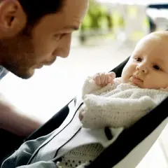 Pappa tittar kärleksfullt på sin bebis i en BabyBjörn babysitter.